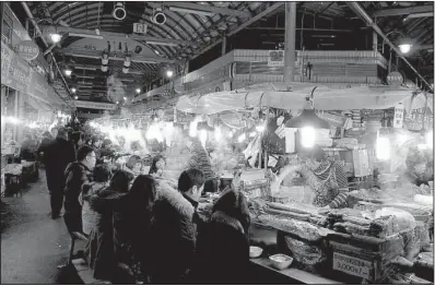  ??  ?? Food stalls in the Gwangjang Market attract visitors in the evenings after shops have closed. A dinner of dumpling soup and side dishes is a typical meal.