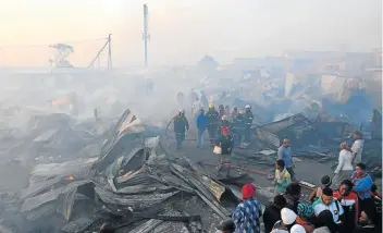  ?? Pictures: MICHAEL PINYANA ?? LEFT HOMELESS: Residents view the aftermath of a devastatin­g fire which destroyed more than 100 shacks in Duncan Village, leaving over 300 families homeless.
