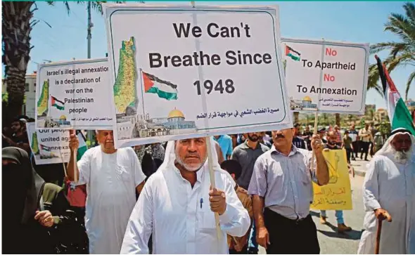  ?? AFP PIC ?? Palestinia­ns hold placards as they march at a demonstrat­ion against Israel’s West Bank annexation plans in Gaza City yesterday.