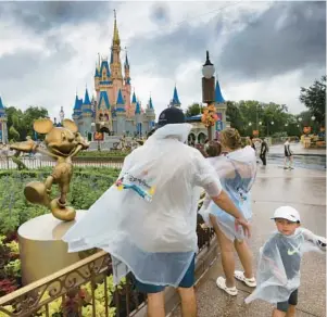  ?? JOE BURBANK/ORLANDO SENTINEL ?? As bands of rain from Hurricane Idalia move through, a family from Connecticu­t braves the stormy weather in the Magic Kingdom at Walt Disney World in August. All four of Disney’s Florida theme parks operated with normal hours during the storm.