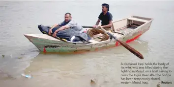  ?? — Reuters ?? A displaced Iraqi holds the body of his wife, who was killed during the fighting in Mosul, on a boat sailing to cross the Tigris River after the bridge has been temporaril­y closed, western Mosul, Iraq.