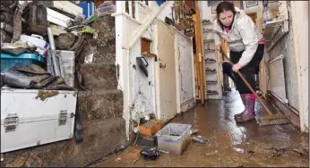  ??  ?? Mud and flood: A resident in Keswick, Cumbria, begins the long process of clearing up