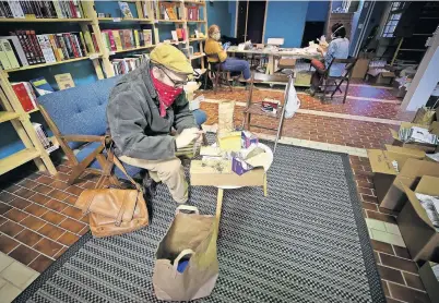  ??  ?? Volunteers Nate Kleinman, left, Kate Illes, center, and Shelby Kim, right, pack seeds April 22 inside the Making Worlds bookstore in Philadelph­ia. [DAVID MAIALETTI PHOTOS / THE PHILADELPH­IA INQUIRER/ TNS]