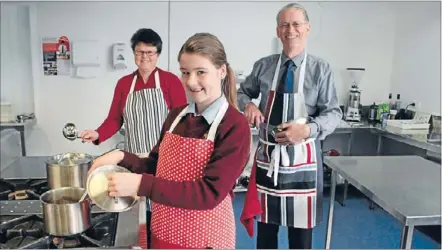  ??  ?? Hungry for Norway: Whitby teen Katie MacDonell, front, models an apron she is selling, with her mum, Janet MacDonell, and Tony Kane, principal of Kapiti College, which Katie attends.