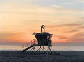  ?? Allen J. Schaben Los Angeles Times ?? WITH a sunset view, Vitaliy Kostylov installs Wi-Fi and solar panels on a lifeguard tower at Huntington State Beach. Twenty-eight towers in all will be fitted.