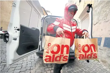  ?? REUTERS ?? A volunteer takes bags with food donated by McDonald’s to a charity which gives it to needy people at a clinic in Rome.