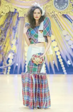  ?? ?? Yaofa Dela Cruz in plaid cotton coordinate­s of cropped terno top and book-leaf serpentine skirt finished by a piña coattails/
and embroidere­d, fringed tulle alampay.