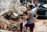  ?? AP PHOTO MARCO UGARTE ?? A woman holds her child as she stands next to wall turned to rubble when it collapsed during a massive earthquake Friday in Mexico City.