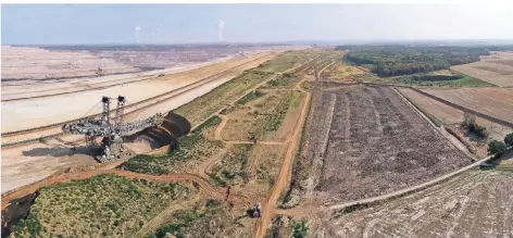  ?? FOTO: DPA ?? Der Hambacher Forst (r.) sollte für den Braunkohle-Tagebau weichen. Im Oktober gab es einen Rodungssto­pp, der Aktienkurs von RWE fiel dadurch.