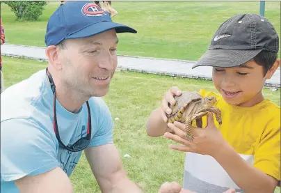  ?? MITCH MACDONALD/THE GUARDIAN ?? Sheldon Opps and his son Elijah, check out one of the turtles at the Bunny Trails Pet Ranch during Old Fashion Carnival that was part of the Summer Days Festival in Georgetown.