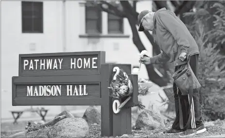  ?? JOSH EDELSON/AP PHOTO ?? Resident Tom Parkinson places flowers on a sign at the Veterans Home of California, the morning after a hostage situation in Yountville, Calif., on Saturday. A daylong siege at The Pathway Home ended Friday evening with the discovery of four bodies, including the gunman, identified as Albert Wong, a former Army rifleman who served a year in Afghanista­n in 2011-12.