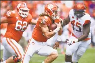  ?? Richard Shiro / Associated Press ?? Clemson quarterbac­k Trevor Lawrence scrambles out of the pocket with blocking help from Cade Stewart (62) as Syracuse’s Kenneth Ruff chaes during the first half on Saturday in Clemson, S.C. Clemson won 27-23.