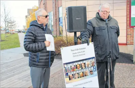  ?? KATHERINE HUNT/SALTWIRE NETWORK ?? Speaker George Gilliland, a retired Chaplin at the Queen Elizabeth Hospital, points to the photos of the victims of the Pittsburgh synagogue attack during the vigil held at Founder’s Hall on Sunday. On the left is P.E.I. Jewish Community president Leo Mednick.