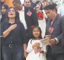  ??  ?? Isabella Basinang (middle), a 6yearold Daly City resident, recites the Pledge of Allegiance alongside her parents, Marienilla Basinang (left) and Glen Basinang (right), at Children's Fairyland.