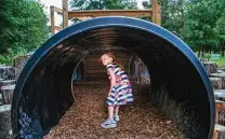  ??  ?? Eloise Rotolo, 7, checks out a tunnel. The playscape is geared to nature play rather than convention­al playground equipment.