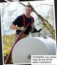  ??  ?? Firefighte­r Lee Jones tops up one of the water containers.