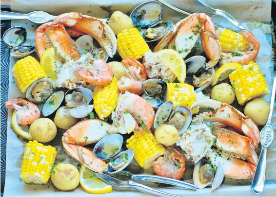  ??  ?? Roll up your sleeves before digging into this delicious seafood boil, featuring B.C. crab, prawns and clams.