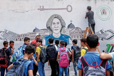  ?? ?? Schoolchil­dren watch as Palestinia­n artists paint a mural honouring slain journalist Shireen Abu Akleh in Khan Younis on Saturday. — afp