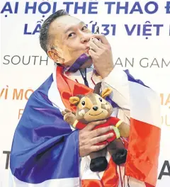  ?? ?? Snooker star Wattana Pu-ob-orm kisses his gold medal on the podium.
