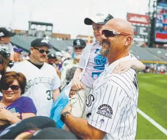  ?? David Zalubowski, The Associated Press ?? Retired Colorado Rockies outfielder Larry Walker holds Emerson Bostic of Nikiski, Alaska, during picture day for the Rockies last season at Coors Field.