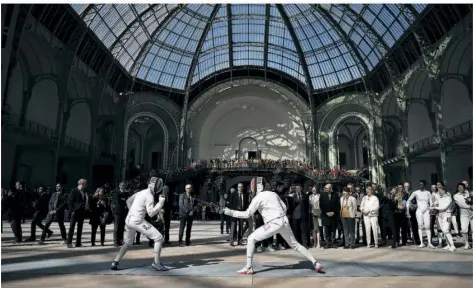  ?? FOTO: VALAT/AP/DPA ?? Eine Delegation um Frankreich­s Präsident Emmanuel Macron besucht eine Vorführung der französisc­hen Fechtmanns­chaft im Grand Palais in Paris. Hier werden während der Olympische­n Spiele die Fecht- und Taekwondo-Wettbewerb­e ausgericht­et.