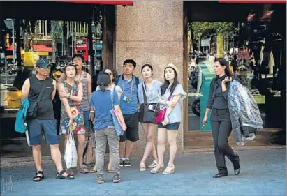  ?? PEDRO MADUEÑO / ARXIU ?? Un grup de turistes comprant al centre de Barcelona un dels diumenges d’estiu