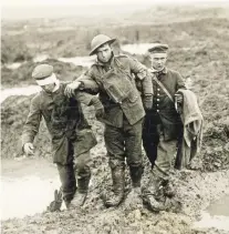  ?? LIBRARY AND ARCHIVES CANADA ?? Surviving soldiers from the two sides make their way together in the aftermath of the bloody 1917 battle at Passchenda­ele, Belgium.