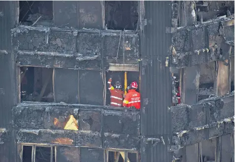  ??  ?? Workers continue to investigat­e Grenfell Tower, above. Nearby, a sign on Lancaster Road has had the word ‘Royal’ removed and replaced by ‘Rotten’