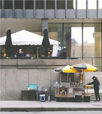  ?? GALIT RODAN / BLOOMBERG FILES ?? Patrons dine at an outdoor restaurant near the Toronto-Dominion Bank Tower while a street vendor waits for customers below in the financial district of Toronto in late March as the third wave of coronaviru­s forced lockdowns.