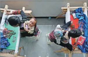  ?? HUA XIAOFENG / FOR CHINA DAILY ?? Women embroider with babies on their backs at a workshop in Meigu county of Liangshan Yi autonomous prefecture, Sichuan province, on Aug 31. Authoritie­s introduced embroidery businesses from Foshan, Guangdong province, to help local women find employment close to home.