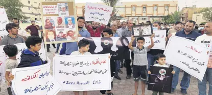  ?? ?? Families of victims hold signs as they demand justice for those missing and the dead found in mass graves, Tarhuna, Libya, Oct. 9, 2021.