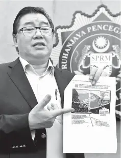  ??  ?? Huan shows the report to reporters when met at the MACC headquarte­rs. — Bernama photo