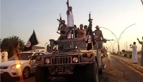  ?? ?? Des combattant­s du groupe État islamique défilent dans un véhicule blindé réquisitio­nné des forces de sécurité irakiennes à Mossoul, dans le nord de l'Irak, le 23 juin 2014.