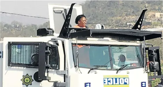  ?? / MANDLA KHOZA ?? Mpumalanga premier Refilwe Mtsweni tries to address the community of KaNyamazan­e from inside a police nyala.