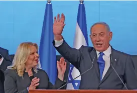  ?? (AFP) ?? Israel’s ex-premier and leader of the Likud party Benjamin Netanyahu addresses supporters, flanked by his wife Sara, at campaign headquarte­rs in Jerusalem early on Wednesday