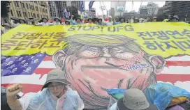  ?? LEE JIN-MAN / ASSOCIATED PRESS ?? Protesters shout slogans near a banner showing an illustrati­on of President Donald Trump as they march toward the U.S. Embassy in Seoul, South Korea, after a rally Tuesday in which they demanded peace on the Korean peninsula.