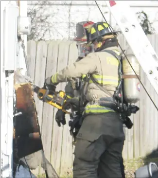  ?? Brodie Johnson • Times-Herald ?? The Forrest City Fire Department responded to a structure fire at 228 Cardinal Drive this morning after a heating lamp left on overnight caused a fire in a home. Firefighte­r Cody Talley uses a chainsaw to cut into the side of the home to access the area where the fire occurred while FCFD Captain Justin Sharp waits to begin removing materials.