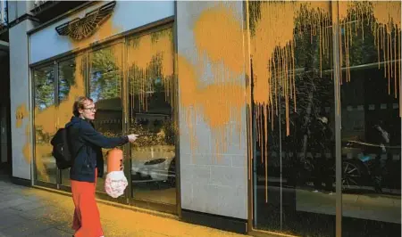  ?? ISABEL INFANTES/GETTY-AFP ?? An environmen­tal activist with Just Stop Oil sprays paint Oct. 16 on the window of an Aston Martin showroom in London.