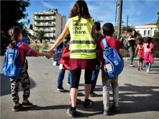  ?? (AFP/Getty) ?? Volunteers walk a group of refugee children towards their school