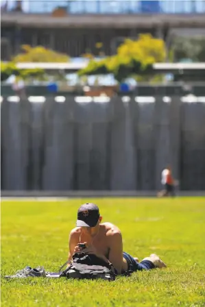  ?? Lea Suzuki / The Chronicle ?? Stephen Gardner of San Francisco makes a phone call to raise donations for a homeless shelter project while enjoying the sun at Yerba Buena Gardens.