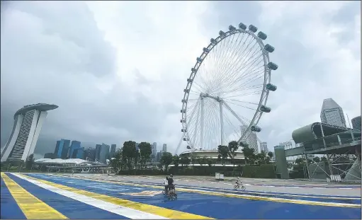  ?? (AP/Annabelle Liang) ?? Cyclists pass by the Singapore Flyer Ferris Wheel attraction in Singapore.
