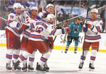  ?? Ben Margot / Associated Press ?? The Rangers’ Kevin Shattenkir­k (center) is congratula­ted after scoring the game-winning shootout goal in a 4-3 victory against the Sharks. It was New York’s fourth win of the season.