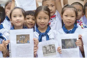  ??  ?? Thai students hold the pictures of the 12 boys and their soccer coach who were trapped in a cave, in front of a hospital in Chiang Rai on Tuesday.