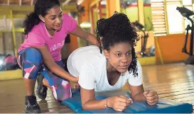  ?? PHOTOS BY GLADSTONE TAYLOR/PHOTOGRAPH­ER ?? Personal trainer Carol McPherson helps Nailah in the plank position.