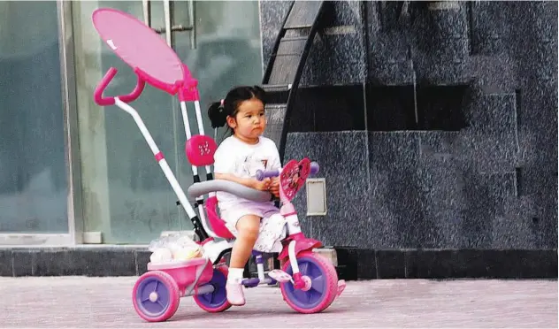  ?? Kamal Kassim/gulf Today ?? A child sits on a fancy tricycle while waiting for her parents.