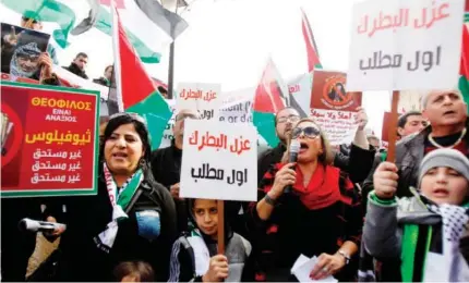  ??  ?? Palestinia­n protesters hold placards as the convoy of Jerusalem's Greek Orthodox patriarch Theophilos III arrives in the West Bank town of Bethlehem on Saturday. (AFP)