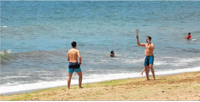  ??  ?? Unos juegan a las palas mientras que otras personas prefieren darse un refrescant­e baño, el primero del año, tras meses de confinamie­nto en casa.