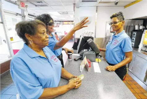  ?? STAFF PHOTOS BY DAN HENRY ?? Alma Carter and Tina Lindsay, from left, order breakfast from General Manager Trella Neal at Krystal.