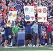  ?? AP FILE ?? Using coach-to-player technology would rid college football sidelines of the need to use placards and signs to signal plays to the field — and sign-stealing.