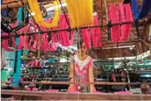  ??  ?? This photo shows a woman weaving silk on a loom for traditiona­l Myanmar clothing at a workshop in Mandalay.